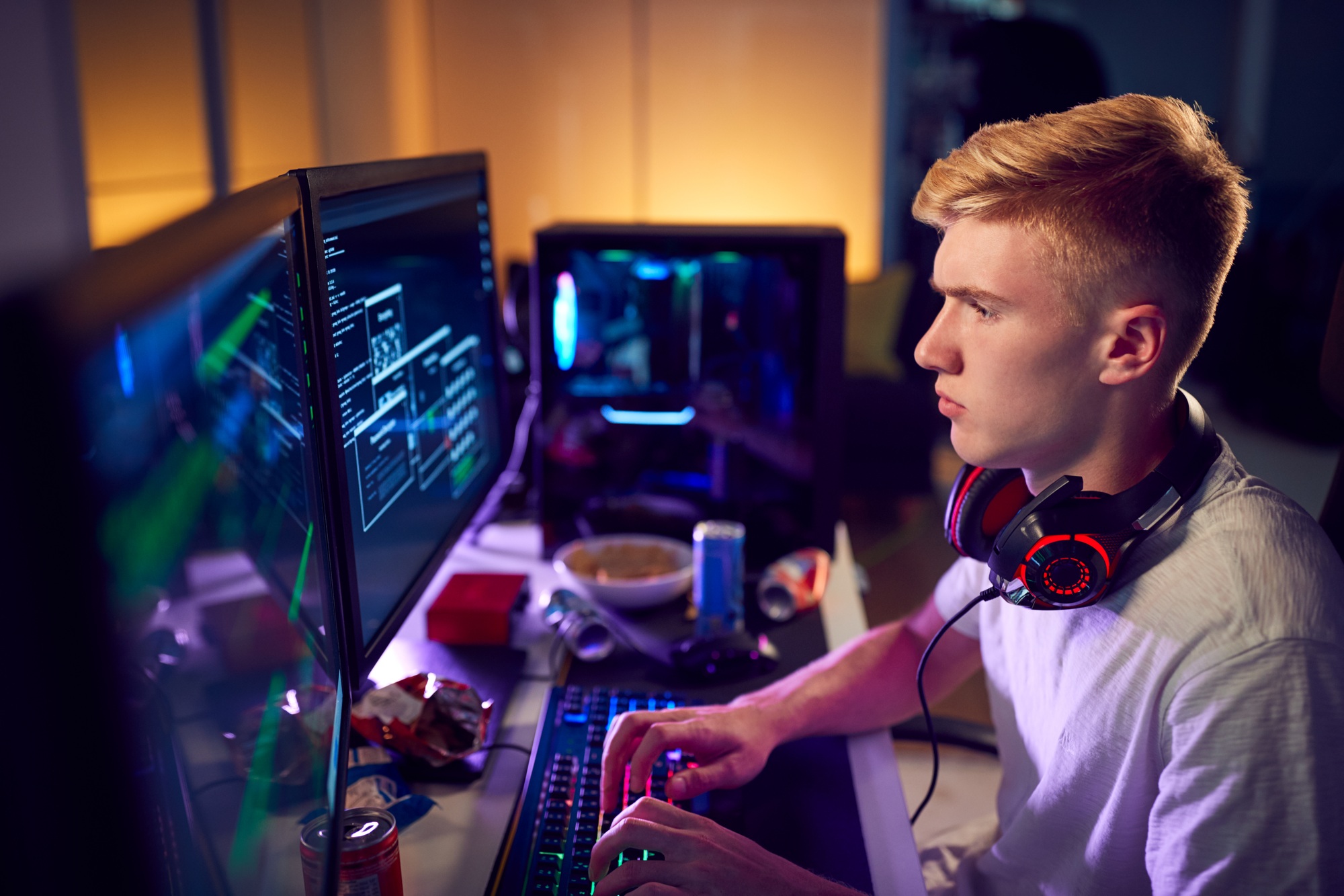 Male Teenage Hacker Sitting In Front Of Computer Screens Bypassing Cyber Security